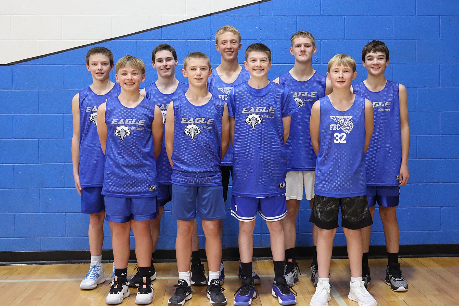 Fairfield Basketball Club eighth-grade boys team posing in blue Eagle jerseys in front of a gym wall